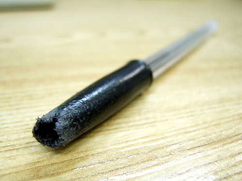 A chewed pen sits on a wooden desk