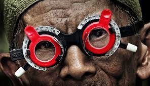 A man from The Look fo Silence with red glasses on looking into the camera