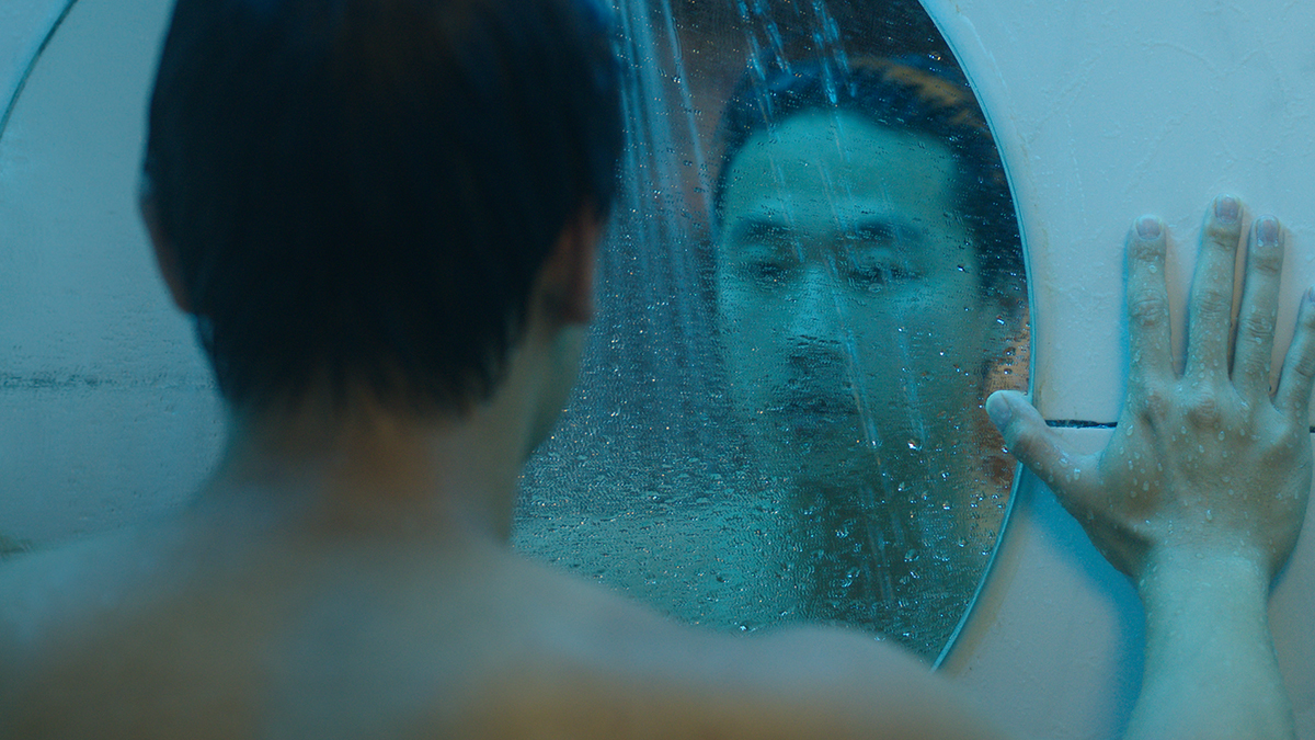 A man looking in the mirror in a still from the movie Spa Night.