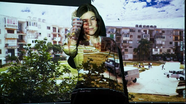 Katerina Cizek covering a part of her face posing in front of a screen projector