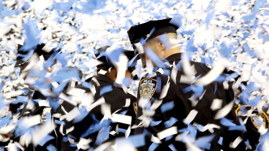 NYPD officers are covered in confetti at a police academy graduation in the documentary Crime + Punishment.