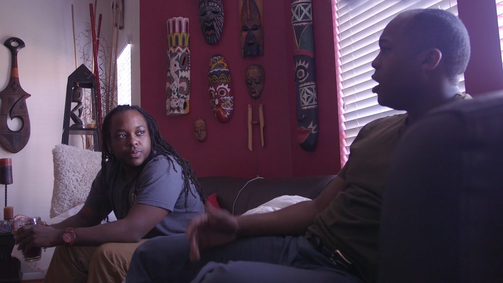 Two people sitting on a couch and talking.