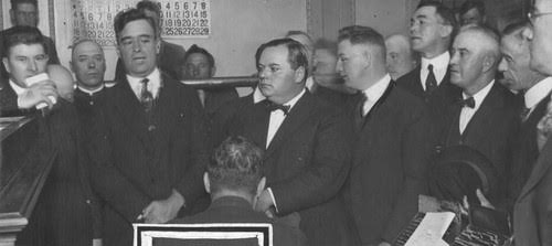 A black and white photo of several men at a press conference.