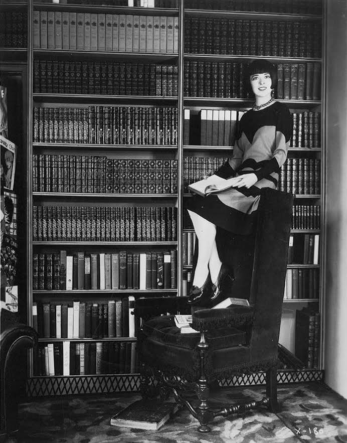 A black and white photon of a woman sitting at the top of a chair.