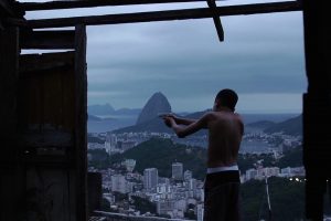 A kid stands up on a hill holding a paper gun that looks like a real gun in the Maria Ramos documentary Hill of Pleasures