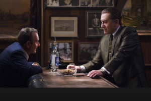 Joe Pesci and Robert De Niro leaning across a table to talk to each other in the movie The Irishman