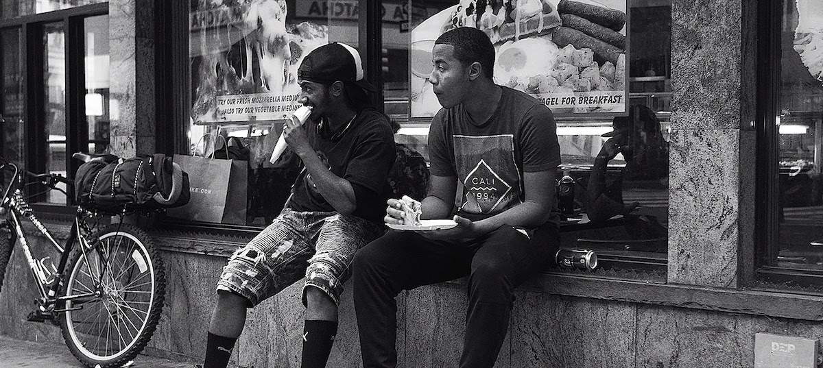 A black and white photo of Bam and Rawls grabbing a slice