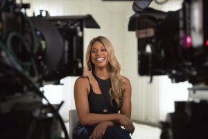 Leverne Cox smiles while sitting between two cameras in the documentary Disclosure: Trans Lives on Screen