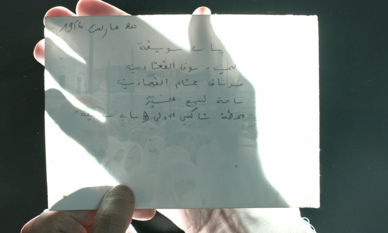 Film still of text on paper with shadow of hand.