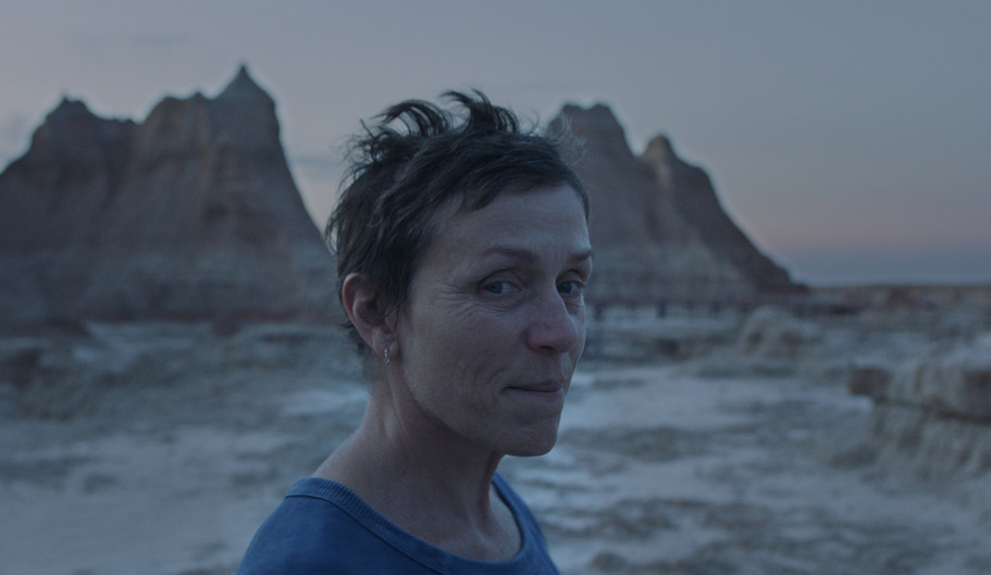 Frances McDormand on a beach staring at camera.