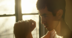 A young man with arms raised is ready to box. 