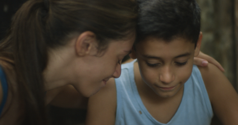 A young woman smiles and holds her younger brother.