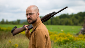 Man stands outside with a gun held on his shoulder. 