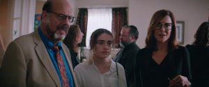 A father, daughter, and mother stand inside during a funeral. 