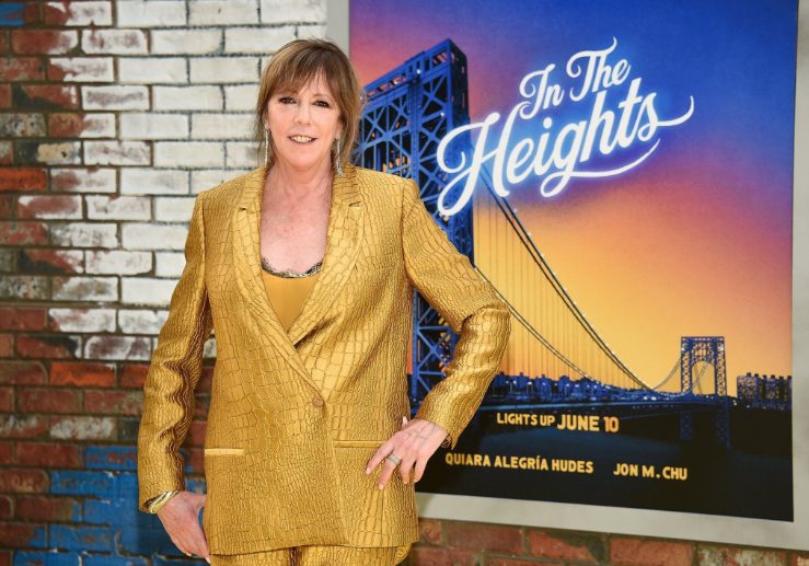 Jane Rosenthal in gold suit in fron of an In the Heights poster.