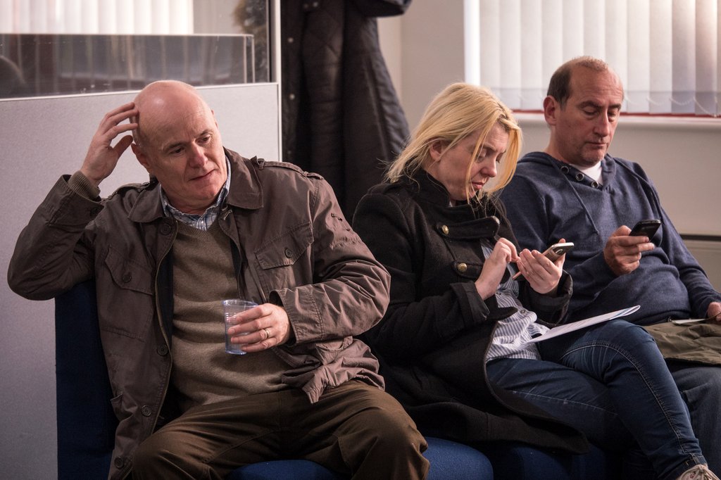 Three people sit in medical waiting room.