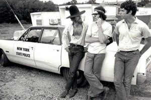 Three men leaning on a police car