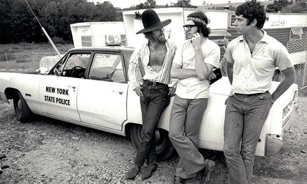 Three men leaning on a police car