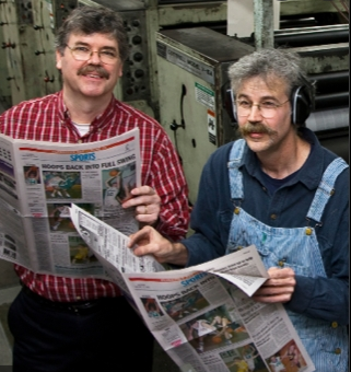 Two men reading newspapers.
