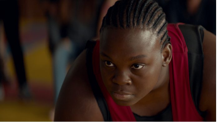 Close-up of Deborah Lukumuena's face as she poses in wrestling pose.