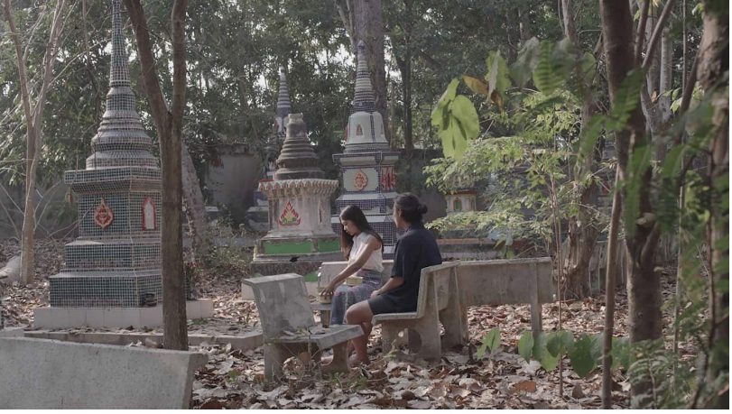 Two people sitting in the woods.