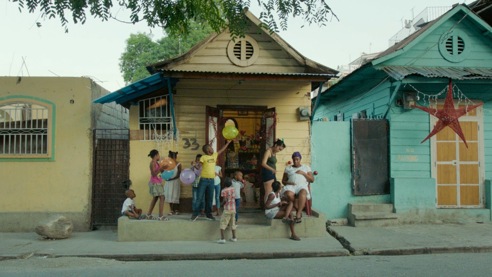 Children playing with balloons in front of a house.