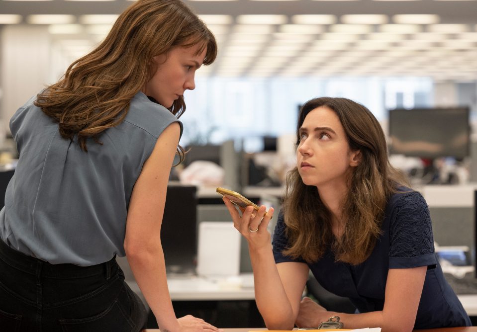 Two women listening to a message on a mobile phone.