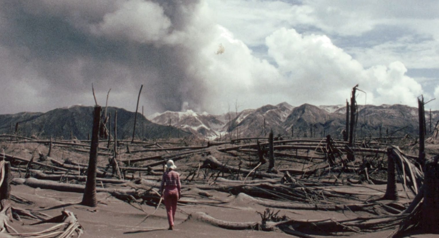 A person walking through the destruction from a volcano.