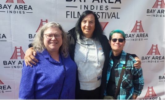 Three people standing in front of wallpaper that says Bay Area Indies Film Festival.