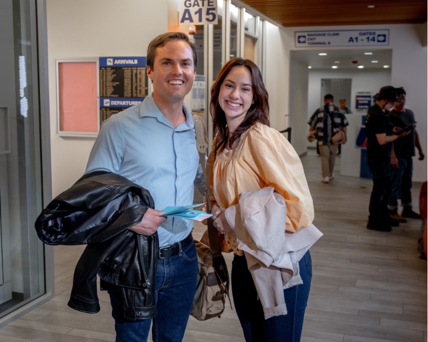 Two actors standing together and smiling.