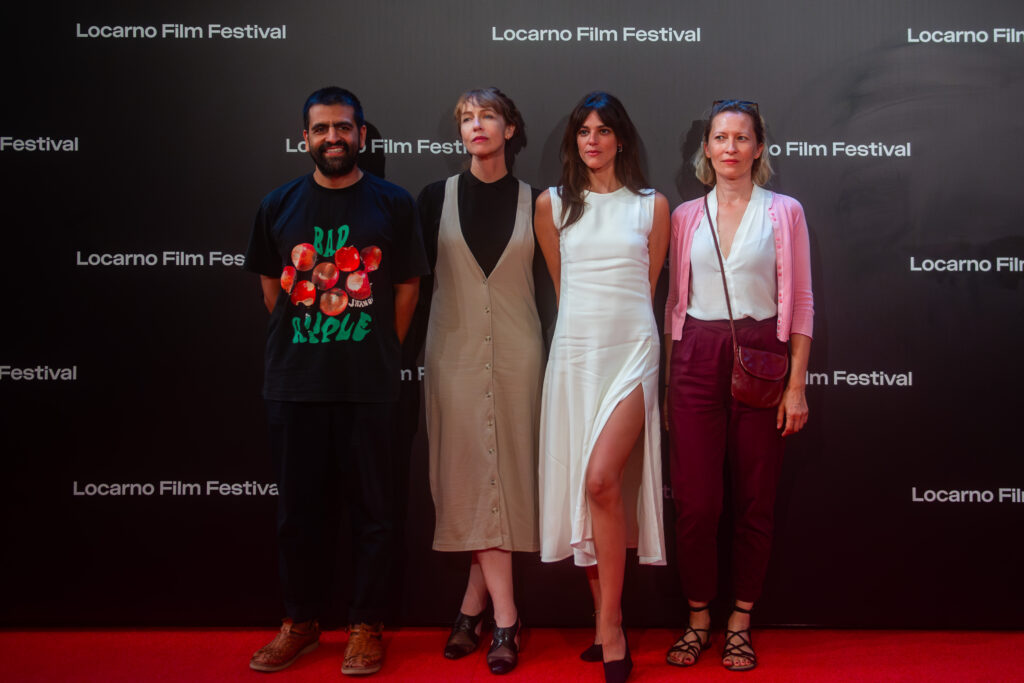 Four people standing on red carpet.