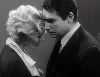 Delphine Seyrig and Robert Hossein staring at one another.