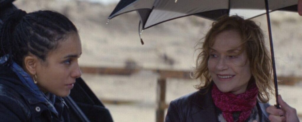 Hafsia Herzi and Isabelle Huppert under an umbrella.