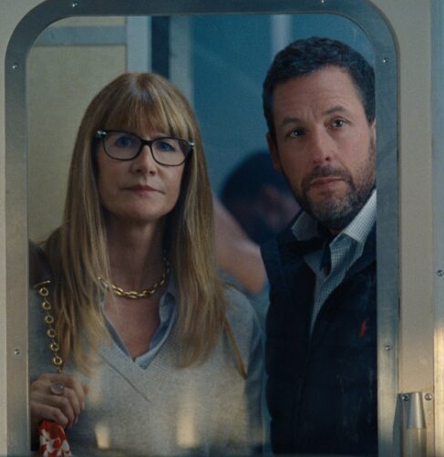 Laura Dern and Adam Sandler staring through a window.