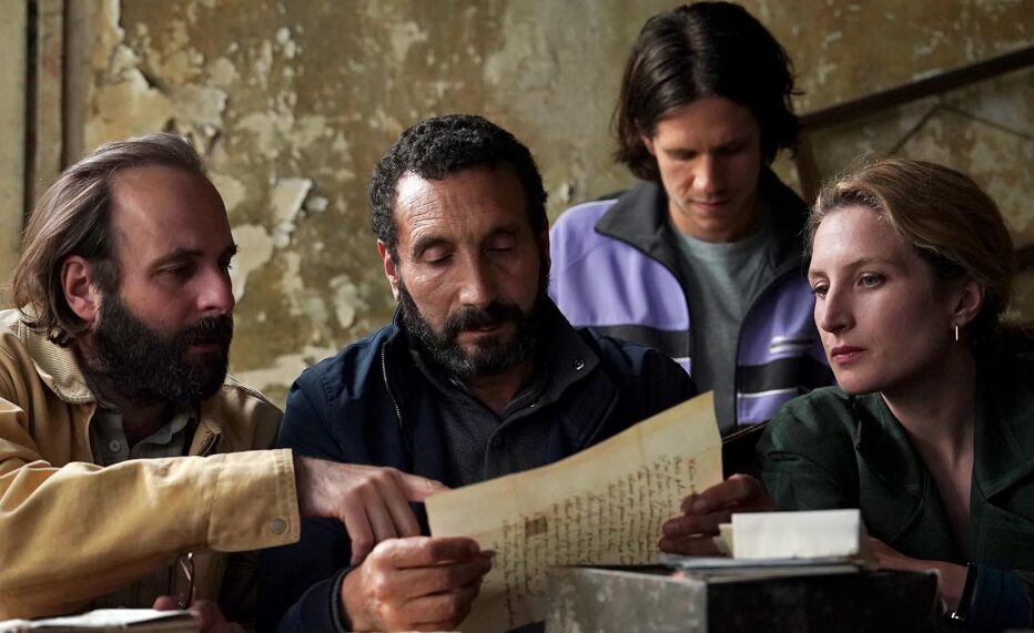 Four people looking at an old document.